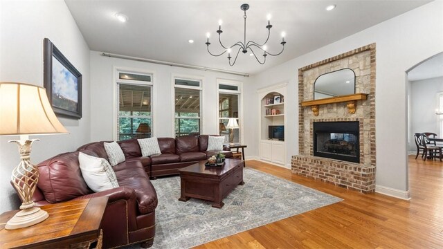 4903 S Inglewood Rd, Rogers, AR 72758 - living area with built in features, wood finished floors, a brick fireplace, a chandelier, and recessed lighting