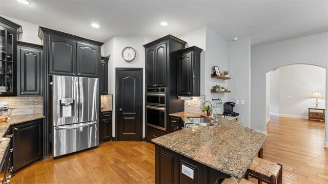 4903 S Inglewood Rd, Rogers, AR 72758 - kitchen with stainless steel appliances, arched walkways, a kitchen breakfast bar, decorative backsplash, and recessed lighting
