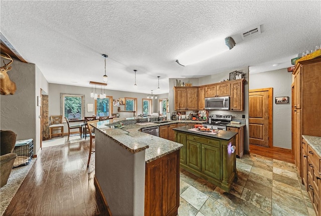 19123 Nokes Farm Rd, Siloam Springs, AR 72761 - kitchen featuring appliances with stainless steel finishes, brown cabinets, a kitchen island, a peninsula, and hanging light fixtures