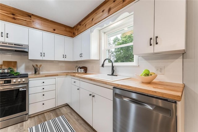 1916 S 12th St, Rogers, AR 72758 - kitchen with appliances with stainless steel finishes, exhaust hood, backsplash, white cabinetry, and light wood finished floors