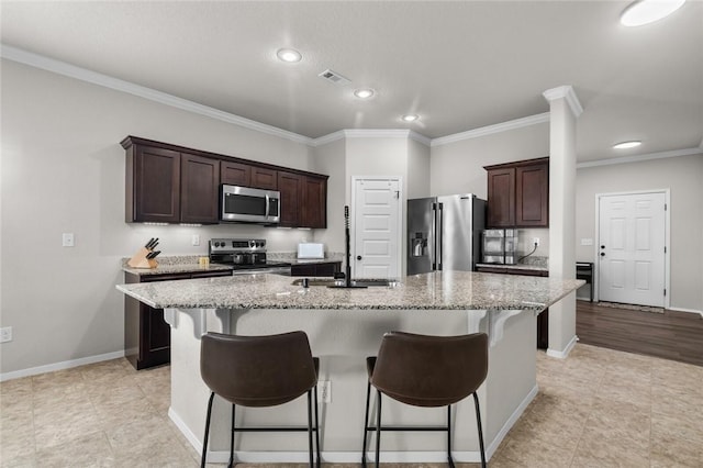 4424 Cornwall St, Springdale, AR 72762 - kitchen with stainless steel appliances, crown molding, dark brown cabinetry, an island with sink, and light stone countertops