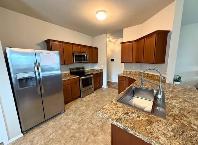 808 NW 69th Ave, Bentonville, AR 72713 - kitchen with stainless steel appliances, stone counters, a peninsula, brown cabinets, and light floors