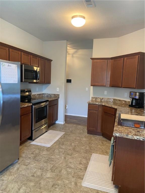 808 NW 69th Ave, Bentonville, AR 72713 - kitchen featuring stainless steel appliances, dark stone countertops, and light floors