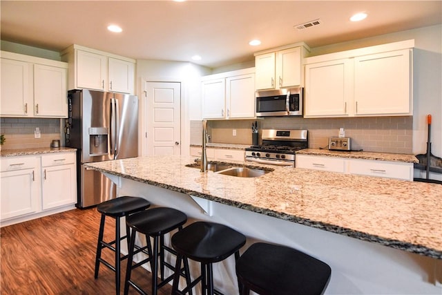 2756 Cassidy Ave, Springdale, AR 72764 - kitchen featuring appliances with stainless steel finishes, dark wood-style floors, a kitchen breakfast bar, tasteful backsplash, and recessed lighting