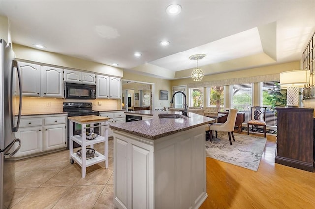 4 Skelton Dr, Bella Vista, AR 72715 - kitchen featuring black microwave, electric range, freestanding refrigerator, a tray ceiling, and backsplash
