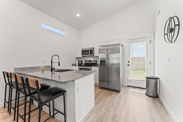671 St Charles Pl, Bentonville, AR 72713 - kitchen with stainless steel appliances, a kitchen bar, healthy amount of natural light, light wood-type flooring, and recessed lighting
