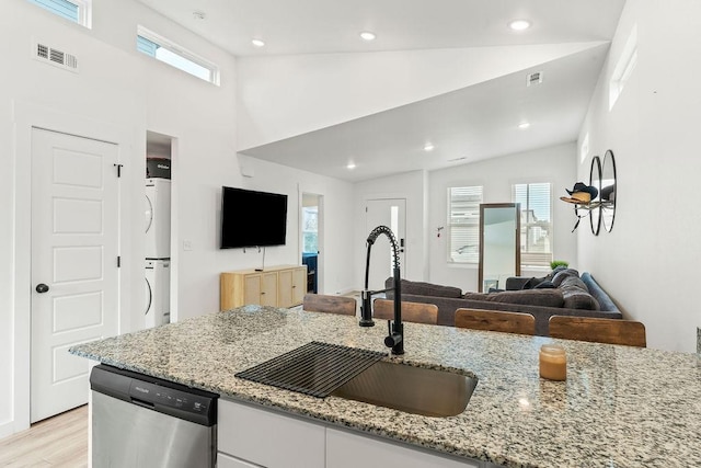 671 St Charles Pl, Bentonville, AR 72713 - kitchen featuring stainless steel dishwasher, estacked washer and dryer, open floor plan, white cabinets, and light stone counters