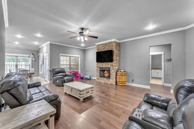1315 W Magnolia St, Rogers, AR 72758 - living room with a ceiling fan, wood finished floors, a stone fireplace, ornamental molding, and recessed lighting