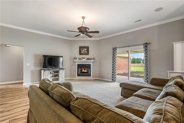 372 Niagara St, Elm Springs, AR 72762 - living room featuring ornamental molding, ceiling fan, a warm lit fireplace, and light wood-style flooring