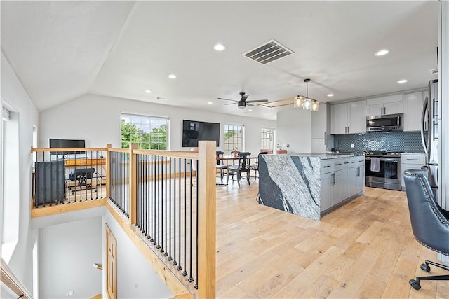 11 Darian Dr, Bentonville, AR 72712 - kitchen with appliances with stainless steel finishes, a ceiling fan, light wood finished floors, a kitchen island, and tasteful backsplash