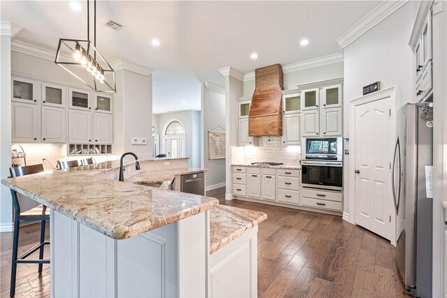 11 Darian Dr, Bentonville, AR 72712 - kitchen featuring stainless steel appliances, custom range hood, crown molding, decorative backsplash, and a kitchen breakfast bar