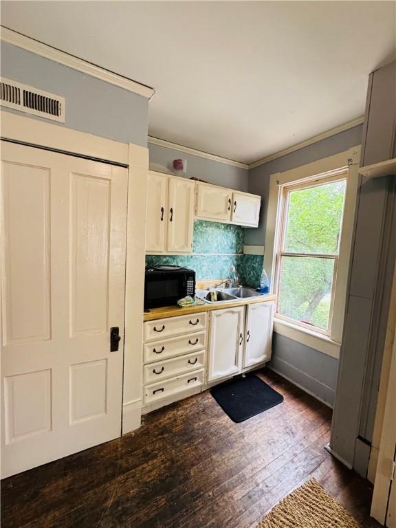 1 Ridgeway Ave, Eureka Springs, AR 72632 - kitchen featuring black microwave, ornamental molding, dark wood-type flooring, white cabinetry, and backsplash