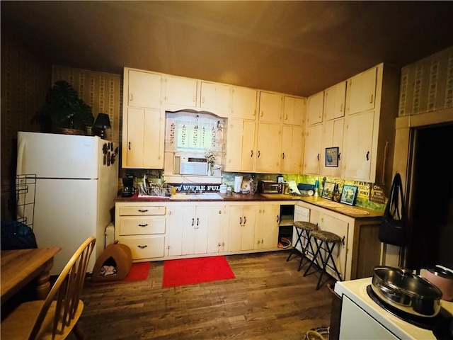 1 Ridgeway Ave, Eureka Springs, AR 72632 - kitchen with freestanding refrigerator, dark wood finished floors, decorative backsplash, and white cabinets