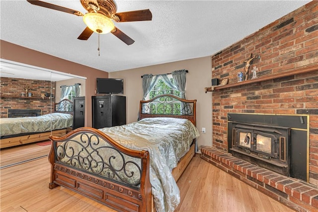 594 Madison 8650, Huntsville, AR 72740 - bedroom featuring a brick fireplace, a textured ceiling, wood finished floors, and ceiling fan