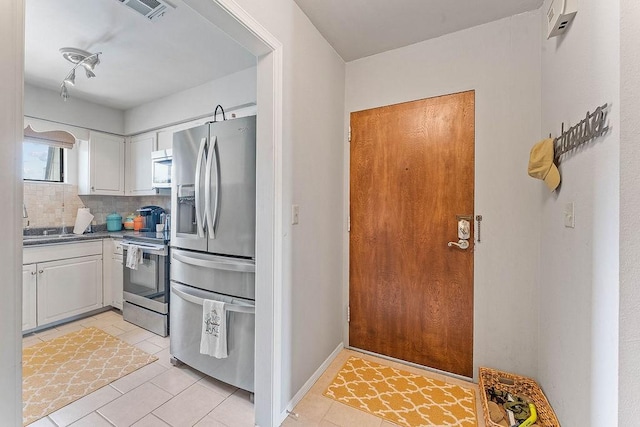 16841 Heritage Bay Rd Unit E-4, Rogers, AR 72756 - kitchen with appliances with stainless steel finishes, light tile patterned flooring, white cabinets, tasteful backsplash, and dark countertops