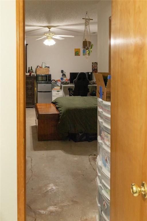 1013 N 26th St, Rogers, AR 72756 - bedroom with an office area, fridge, unfinished concrete floors, and ceiling fan