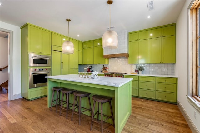 300 NW 5th St, Bentonville, AR 72712 - kitchen featuring green cabinetry, wood finished floors, backsplash, a breakfast bar area, and decorative light fixtures