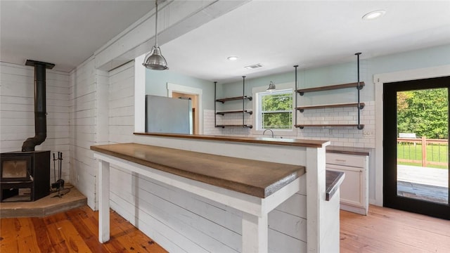 234 N Kibler Hwy, Alma, AR 72921 - kitchen with freestanding refrigerator, a wood stove, light wood-style flooring, open shelves, and white cabinetry