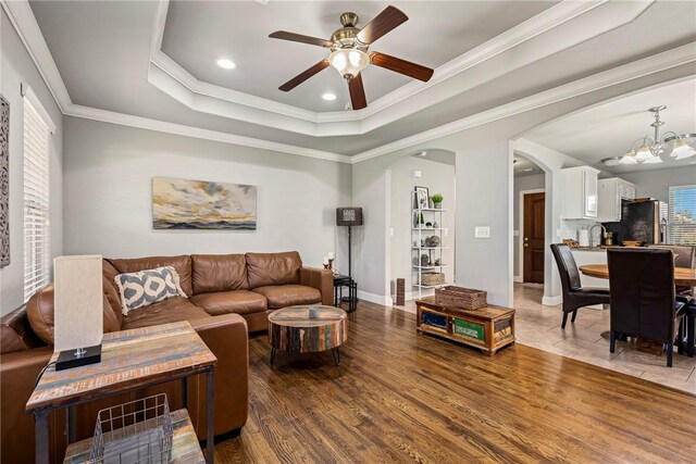 3900 SW Capstone Ave, Bentonville, AR 72712 - living room featuring arched walkways, a chandelier, ceiling fan, a raised ceiling, and wood finished floors