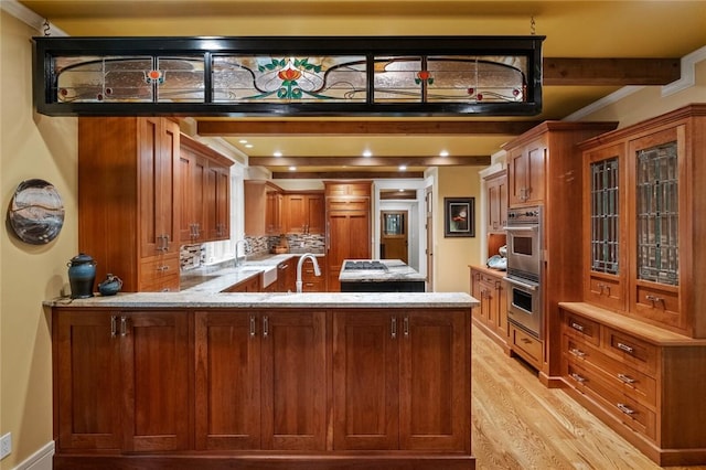 150 Jackson Cove Cres, Eureka Springs, AR 72631 - kitchen with light wood-style flooring, light stone countertops, a peninsula, brown cabinetry, and crown molding