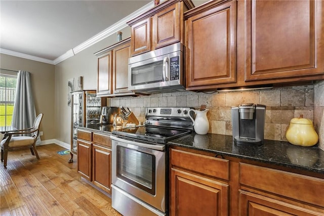 216 Windsor Ave, Lowell, AR 72745 - kitchen with stainless steel appliances, crown molding, light wood-type flooring, decorative backsplash, and brown cabinets