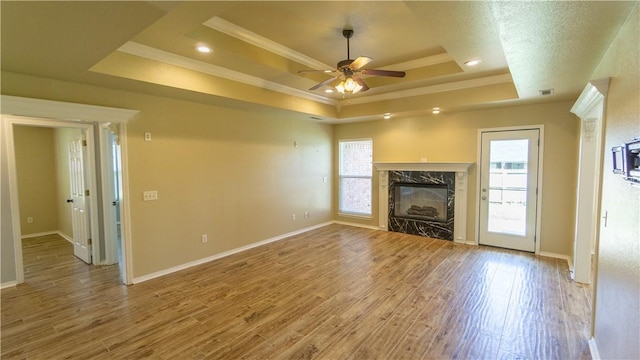 404 NE Whitney St, Bentonville, AR 72712 - unfurnished living room featuring a tray ceiling, ornamental molding, a ceiling fan, a high end fireplace, and wood finished floors