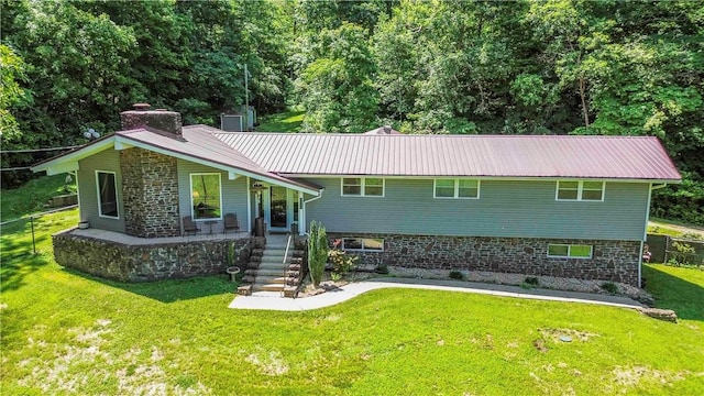 8173 Spanker Creek Rd, Bentonville, AR 72712 - view of front of house featuring a front yard, a metal roof, covered porch, a chimney, and stone siding