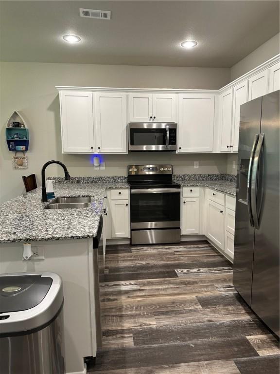 26 Osborne Dr, Bella Vista, AR 72715 - kitchen with stainless steel appliances, a peninsula, white cabinetry, and recessed lighting