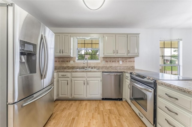 1206 Tru Ln, Rogers, AR 72756 - kitchen featuring appliances with stainless steel finishes, light wood finished floors, backsplash, and a peninsula