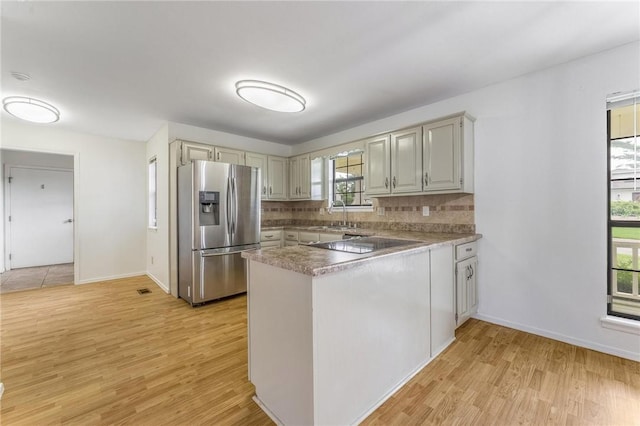 1206 Tru Ln, Rogers, AR 72756 - kitchen with stainless steel fridge, a peninsula, light wood-type flooring, and decorative backsplash