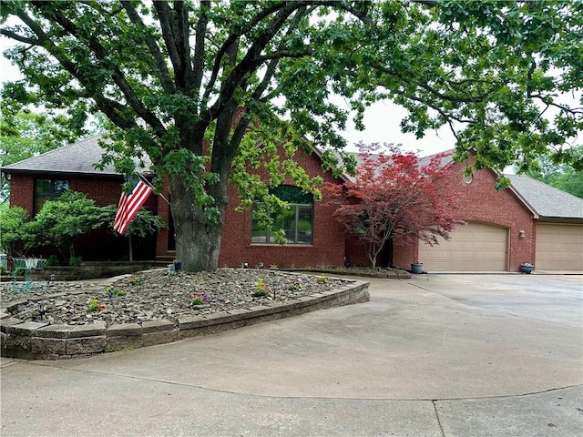 9364 Everest Pl, Rogers, AR 72756 - view of property hidden behind natural elements with brick siding, driveway, a garage, and a shingled roof