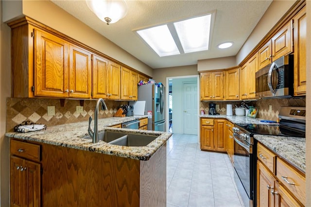 2 Kildonan Ln, Bella Vista, AR 72715 - kitchen featuring appliances with stainless steel finishes, light stone counters, decorative backsplash, light tile patterned floors, and a peninsula