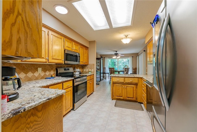 2 Kildonan Ln, Bella Vista, AR 72715 - kitchen with appliances with stainless steel finishes, a peninsula, backsplash, and brown cabinets
