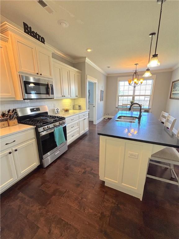 1610 Sweetbriar, Centerton, AR 72719 - kitchen with stainless steel appliances, crown molding, a chandelier, white cabinets, and decorative backsplash