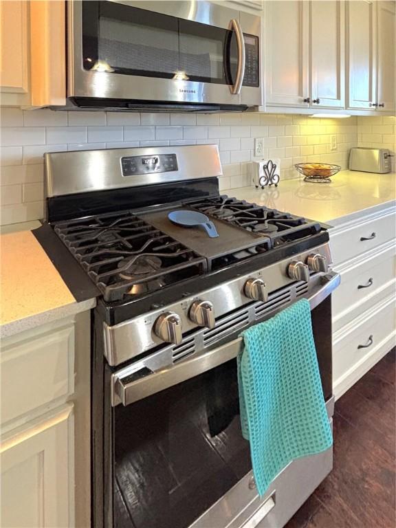 1610 Sweetbriar, Centerton, AR 72719 - kitchen featuring appliances with stainless steel finishes, light countertops, decorative backsplash, and white cabinets