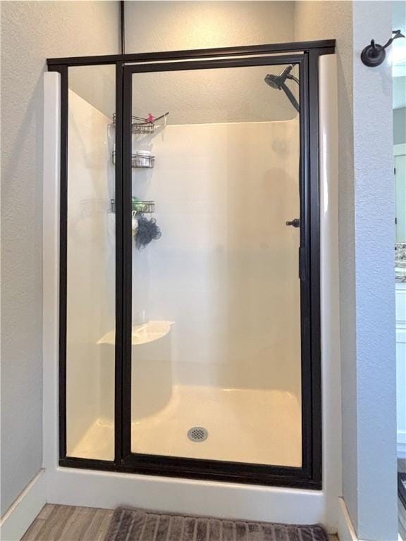 1610 Sweetbriar, Centerton, AR 72719 - bathroom featuring a textured wall, a shower stall, and wood finished floors
