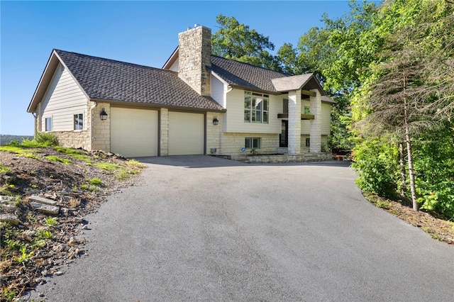 40 Rivercliff Rd, Rogers, AR 72756 - view of front of home with a chimney, a garage, a shingled roof, driveway, and stone siding