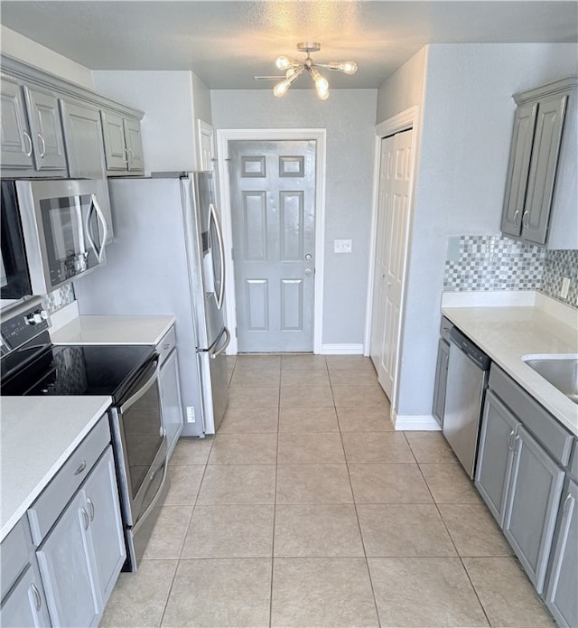 1204 Jim Mcvay, Siloam Springs, AR 72761 - kitchen with gray cabinetry, stainless steel appliances, light countertops, tasteful backsplash, and light tile patterned flooring