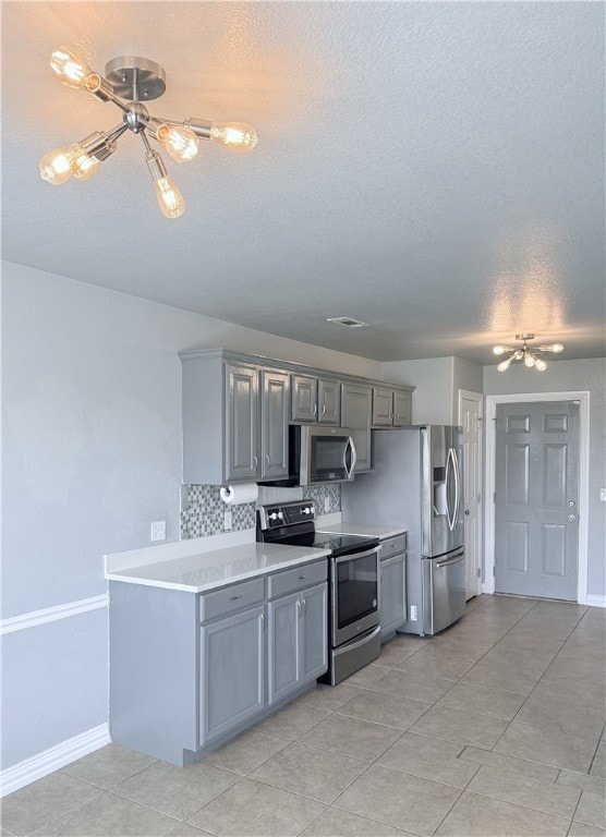 1204 Jim Mcvay, Siloam Springs, AR 72761 - kitchen featuring stainless steel appliances, gray cabinets, decorative backsplash, light countertops, and a textured ceiling
