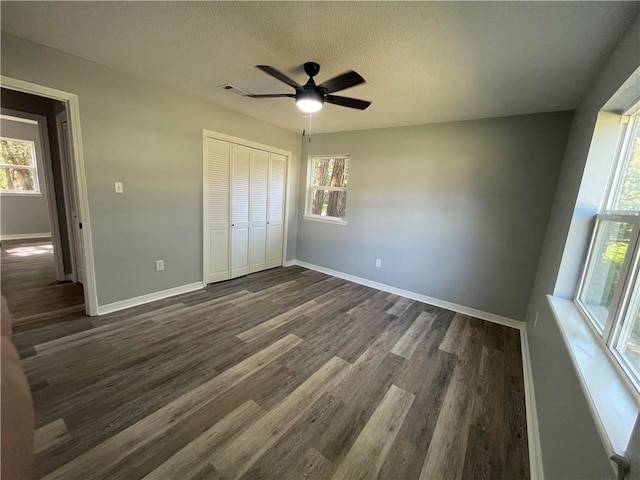 904 E Norristown Cir, Russellville, AR 72802 - unfurnished bedroom featuring dark wood-type flooring, multiple windows, a closet, a textured ceiling, and a ceiling fan