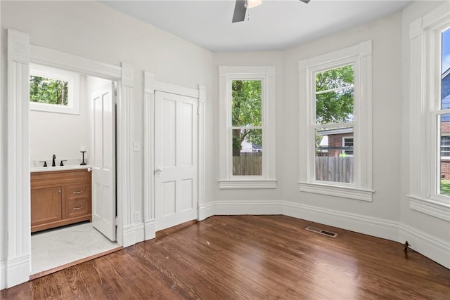 506 E Ashley St, Siloam Springs, AR 72761 - unfurnished bedroom with wood finished floors, ceiling fan, and ensuite bathroom
