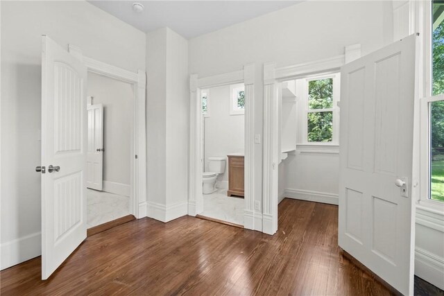 506 E Ashley St, Siloam Springs, AR 72761 - unfurnished bedroom with dark wood finished floors, multiple windows, and ensuite bath