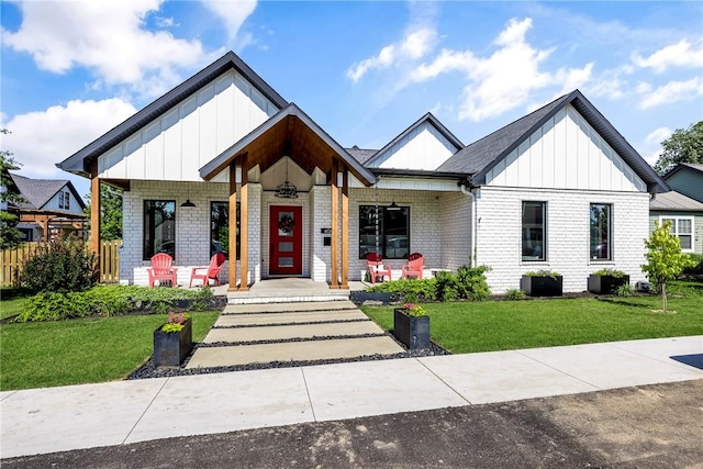406 SW E St, Bentonville, AR 72712 - view of front of home with covered porch, board and batten siding, a front lawn, and brick siding