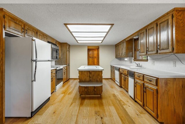 8073 Old White River Rd, Rogers, AR 72756 - kitchen with white appliances, light wood-style floors, light countertops, brown cabinetry, and a textured ceiling