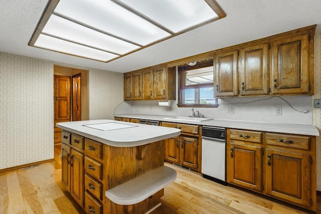 8073 Old White River Rd, Rogers, AR 72756 - kitchen with brown cabinets, wallpapered walls, light wood-style floors, a kitchen island, and light countertops