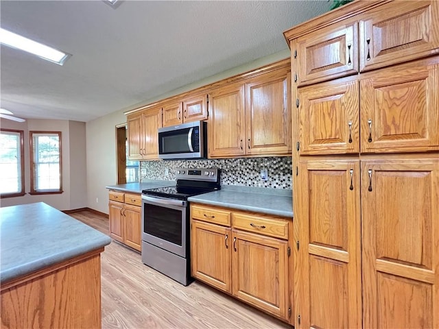 6 Hillcrest Dr, Holiday Island, AR 72631 - kitchen featuring appliances with stainless steel finishes, light wood-style floors, tasteful backsplash, light countertops, and a ceiling fan