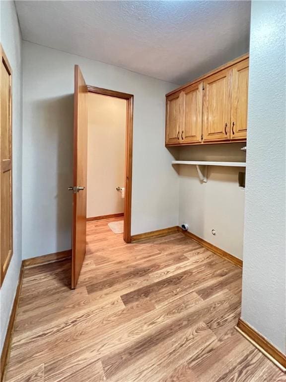 6 Hillcrest Dr, Holiday Island, AR 72631 - laundry area with light wood-type flooring, cabinet space, and a textured ceiling