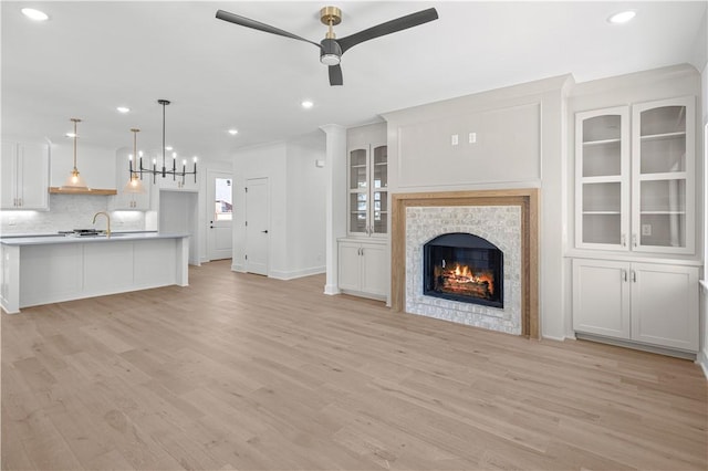 1316 Bella Vista Rd, Bentonville, AR 72712 - unfurnished living room with ceiling fan, light wood-type flooring, recessed lighting, a warm lit fireplace, and a chandelier