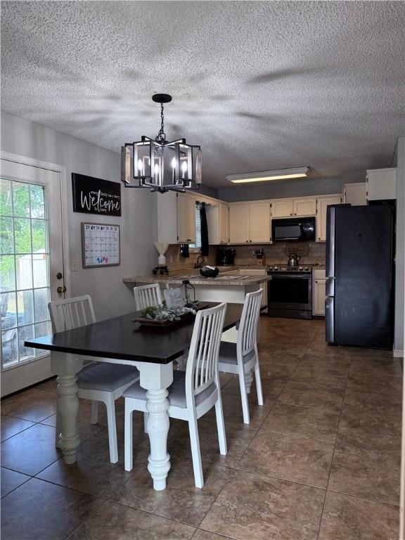 604 W Carver St, Ozark, AR 72949 - dining space featuring a chandelier, a textured ceiling, and dark tile patterned floors