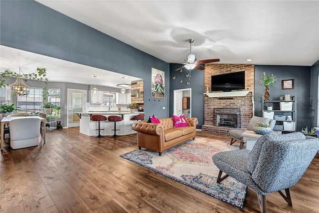 1303 W Pine St, Rogers, AR 72758 - living area featuring wood-type flooring, a brick fireplace, a ceiling fan, a chandelier, and recessed lighting